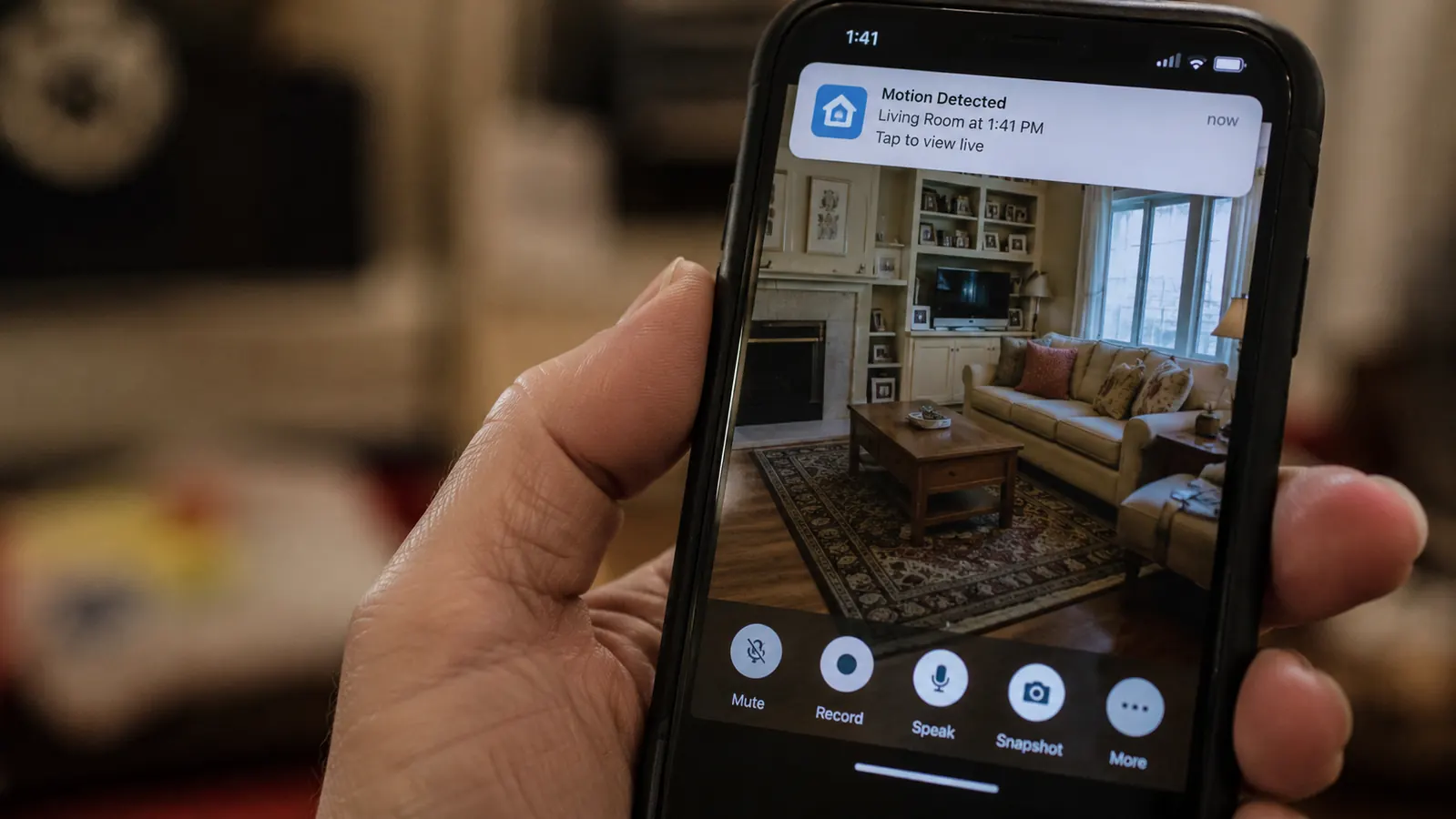 Smartphone screen showing a live camera feed of a living room with motion alert notification