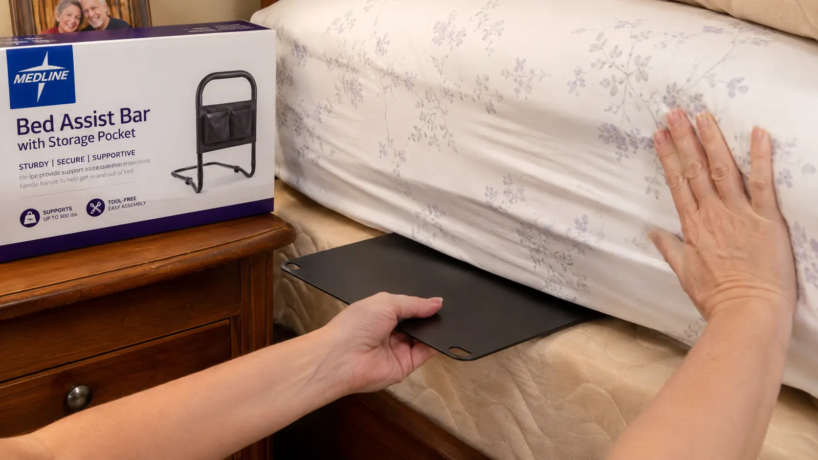 Medline bed assist bar inserted between mattress and box spring, showing the flat base plate tucked under the mattress